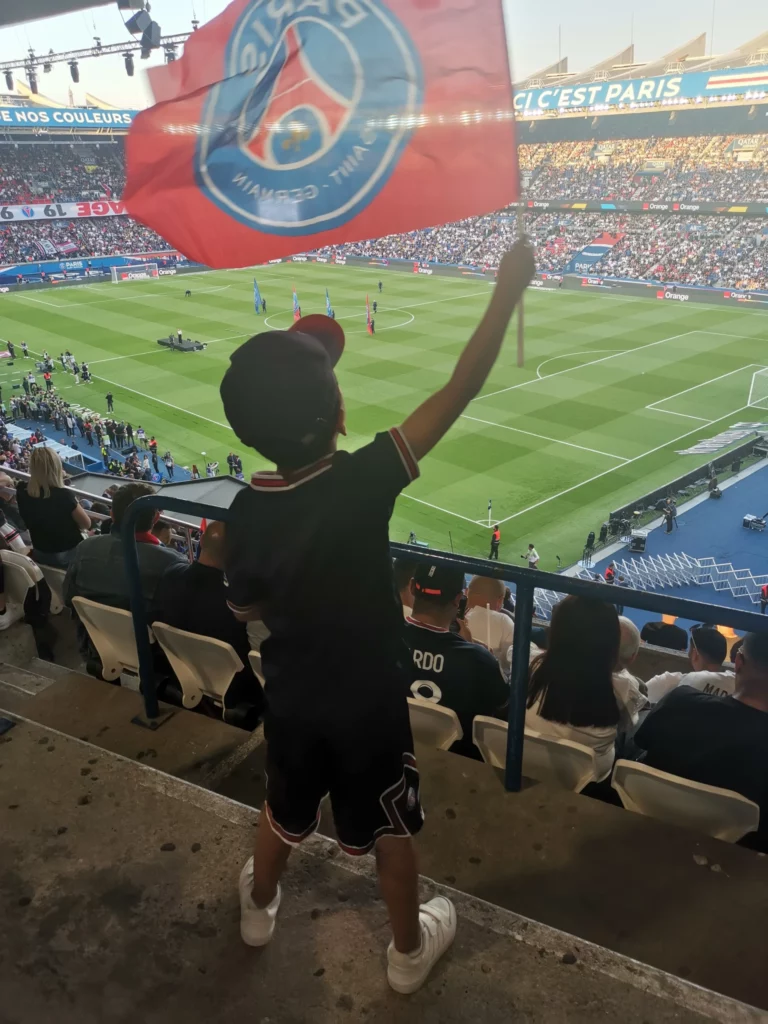 Un jeune supporter du PSG qui tient un drapeau du club dans les tribunes du Parc des Princes